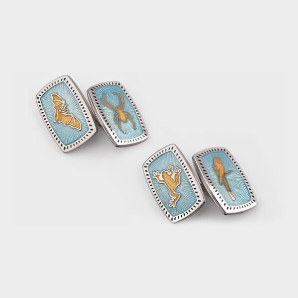 A pair of light blue enamelled cufflinks with different animal designs on them.